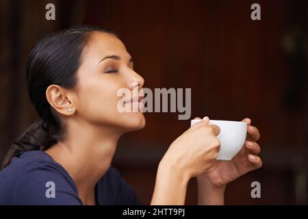 Il delizioso aroma di caffè appena macinato. Una giovane donna che beve una tazza di caffè all'aperto. Foto Stock