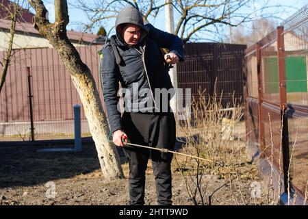 pesti fumigante, controllo della peste. Defocalizzare l'uomo contadino spruzzando albero con pesticida manuale spruzzatore contro gli insetti nel giardino di primavera. Agricoltura e garde Foto Stock