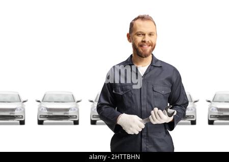 Meccanico di fronte alle auto argentate che tengono una chiave isolata su sfondo bianco Foto Stock