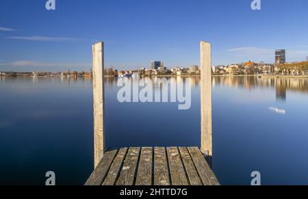 Zug, Svizzera - 31 dicembre 2021: Vista sulla città di Zug sul lago in Svizzera con primo piano sul molo Foto Stock