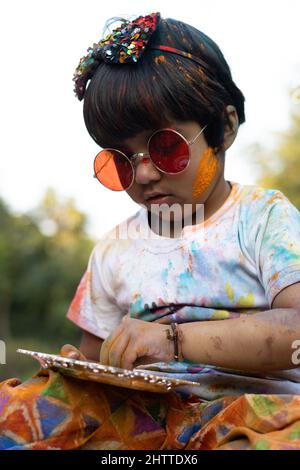 Tema Holi colorato - Ritratto di carino indiano vestendo tondi colori e dipinti in polvere di colore Holi chiamato Rang Gulal Foto Stock