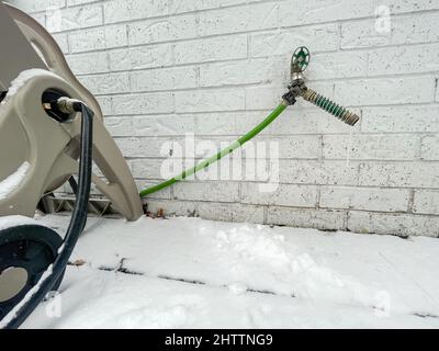 Primo piano di un rubinetto d'acqua surgelata su sfondo bianco muro di mattoni Foto Stock