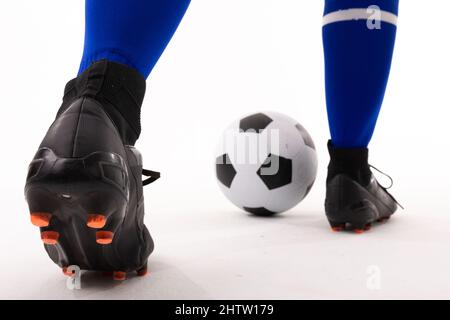 Sezione bassa di giovane femminile biraciale che gioca a calcio su sfondo bianco Foto Stock