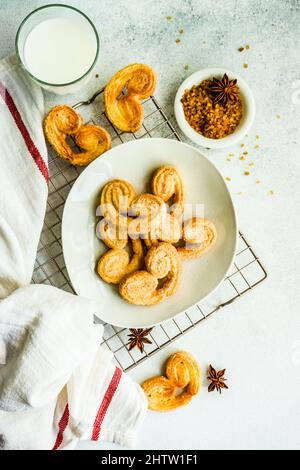 Biscotti a spirale per pasta sfoglia tradizionale conosciuti come orecchie di maiale su piatto con zucchero Foto Stock