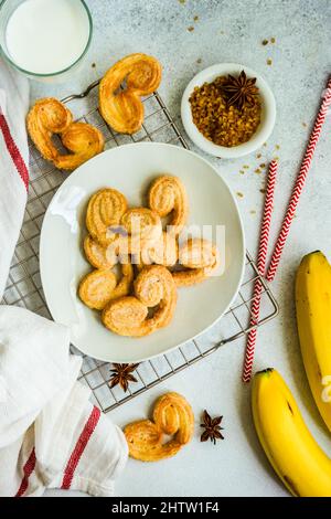 Biscotti a spirale per pasta sfoglia tradizionale conosciuti come orecchie di maiale su piatto con zucchero Foto Stock