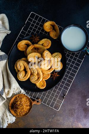 Biscotti a spirale per pasta sfoglia tradizionale conosciuti come orecchie di maiale su piatto con zucchero Foto Stock