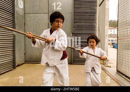 due bambini giocano a karate per strada Foto Stock