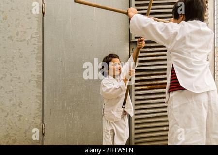 due bambini giocano a karate per strada Foto Stock