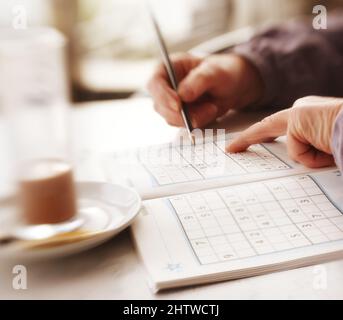 Donna cercando di risolvere Sudoku Puzzle - finestra, luce del sole, e caffè. Donna cercando di risolvere Sudoku Puzzle - finestra, luce del sole, e caffè. Foto Stock