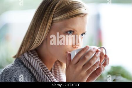 Abbiamo tutti bisogno di un posto per essere soli. Una giovane donna seduta in una caffetteria. Foto Stock