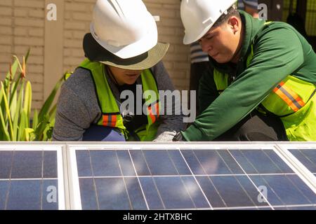 Coppia di tecnici Latino che lavorano su un pannello solare Foto Stock