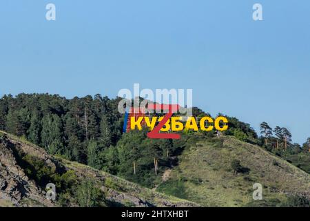 L'iscrizione Kuzbass sulla montagna di fronte alla foresta sulla cima della quale una grande lettera Z è scritta in rosso, fuoco selettivo Foto Stock