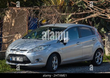 Side, Turchia -13 febbraio 2022: Silver Ford Fiesta è parcheggiata sulla strada in una giornata calda sullo sfondo di un edificio, parco, recinzione Foto Stock