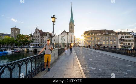 Turista sul ponte Muenster sul fiume Limmat, chiesa Fraumuenster, città vecchia di Zurigo, stella del sole al tramonto, Zurigo, Canton Zurigo, Svizzera Foto Stock