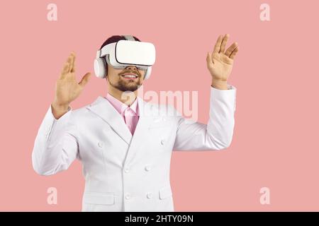 Happy man indossa un visore VR futuristico, sperimentando la realtà virtuale e sorridendo Foto Stock