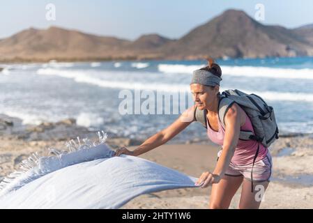 Donna viaggiatore che stendendo asciugamano su spiaggia sabbiosa Foto Stock