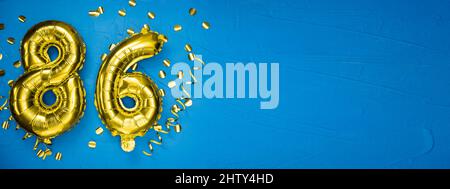 palloncino giallo dorato su fondo di cemento blu numero ottantasei. Tessera di compleanno o anniversario con l'iscrizione 86. Celebratio anniversario Foto Stock