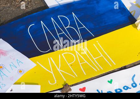 Manifestazione pacifica contro la guerra, Putin e la Russia a sostegno dell’Ucraina con cartelli, bandiere e disegni per bambini. Gloria in Ucraina in Cirillico Foto Stock