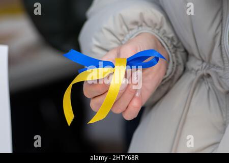 Ragazza che tiene un nastro con colori di Ucraina durante una manifestazione pacifica contro la guerra, Putin e Russia Foto Stock
