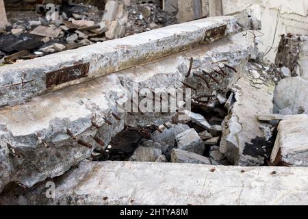 Un mucchio di detriti da costruzione in primo piano di travi in calcestruzzo con raccordi in metallo sporgenti, mattoni e detriti di calcestruzzo grigio. Sfondo. Foto Stock