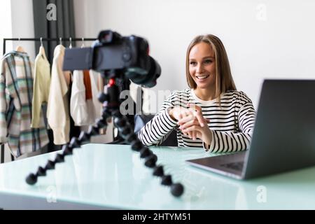 Sicuro vlogger femminile giovane siediti alla scrivania sparando trasmissione dal vivo su fotocamera professionale, successo di altoparlante ragazza millennial o parlare coach parlare reco Foto Stock