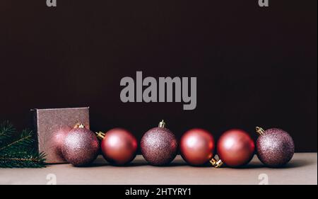 Palline rosa di natale su parete marrone e beige. Elegante sfondo decorativo di Natale. Biglietto d'auguri minimal trendy. Buon natale e felice nuovo yea Foto Stock