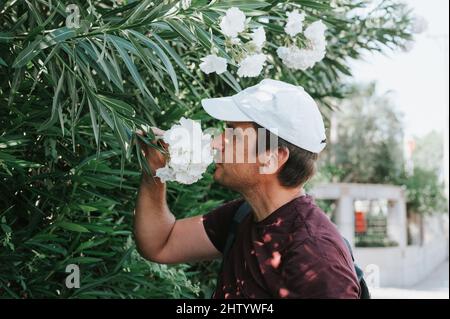 il viaggiatore vero uomo maturo ama il profumo di un fiore in mano durante un viaggio estivo di tutti i giorni. concetto di positiv senza stereotipi Foto Stock