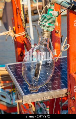 Una lampada alogena con una stazione di ricarica per batterie solari sul ponte di una nave fisher Foto Stock