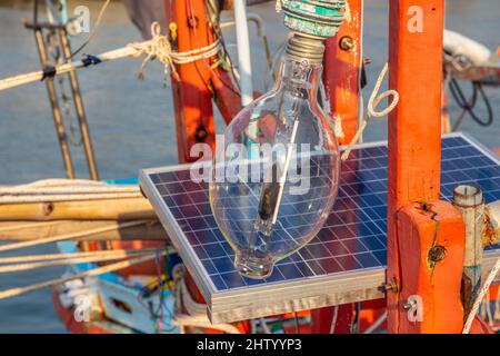 Una lampada alogena con una stazione di ricarica per batterie solari sul ponte di una nave fisher Foto Stock