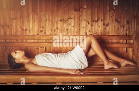 Semplicemente sereno.... Scatto corto di una giovane donna che si rilassa nella sauna di un centro benessere. Foto Stock