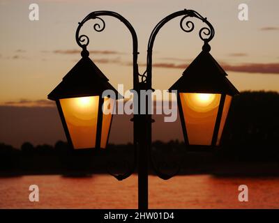 Lanterna in ferro battuto illuminata, come una silhouette di fronte al cielo illuminata dal tramonto sullo sfondo sfocato. Spazio sufficiente sulle finestre Foto Stock