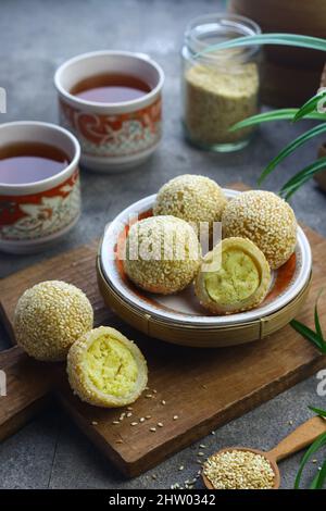 Onde Onde o torta di riso glutinosa sfera di sesamo su piastra di ceramica con tazze di tè. Messa a fuoco selettiva, sfondo grigio granuloso. Foto Stock