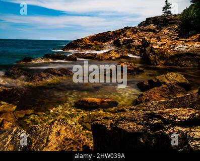 Onde rollin gin sulla riva di pietra Foto Stock