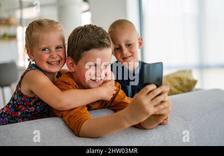 Concetto di smartphone per bambini con tecnologia infantile. Bambini piccoli felici che giocano sul telefono cellulare Foto Stock