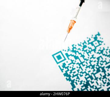 Un primo piano del codice QR e una siringa medica colorata Foto Stock