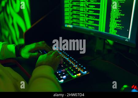 Hacker in Hoodie lavoro hacks codice sito sul personal computer. Concetto di spia di guerra e cyber attacco Foto Stock