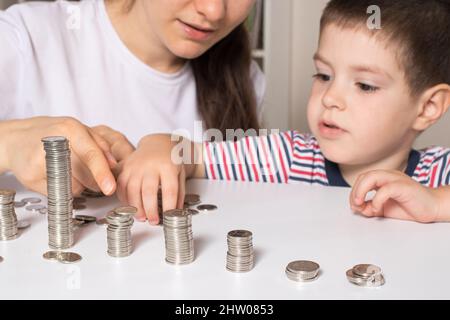 Il genitore insegna al bambino come maneggiare i soldi. Corso di alfabetizzazione finanziaria per bambini in età prescolare e scolastica. Foto Stock