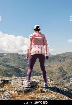 Vista posteriore di una escursionista femminile in piedi al picco Ushite che domina la cima di Malyovitsa nel Parco Nazionale di Rila, montagna di Rila, Bulgaria, Europa Foto Stock