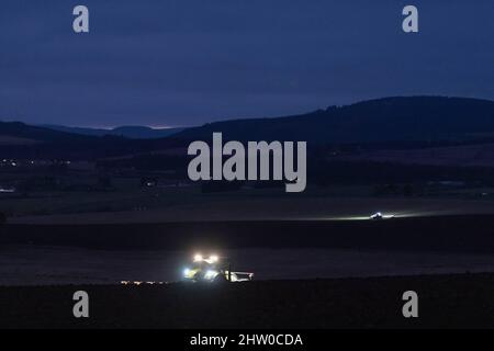 Una vista sui terreni agricoli dell'Aberdeenshire in una serata invernale con due trattori ancora arati dopo il tramonto Foto Stock