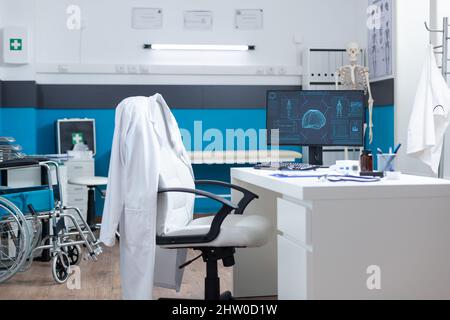 Computer con struttura corporea sullo schermo in piedi sul tavolo in un ufficio medico vuoto durante l'esame dell'anatomia. Luogo di lavoro medico con radiografia scheletrica. Supporto dei servizi sanitari Foto Stock