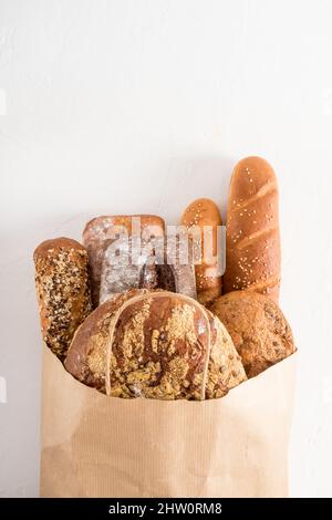 un sacchetto pieno di pane appena sfornato in una panetteria su sfondo bianco. Concetto di zero rifiuti, eco shopping e consegna. Vista piana verticale Foto Stock