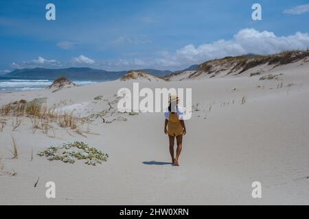 Cape Nature Walker Bay spiaggia vicino Hermanus Western Cape Sud Africa. Spiaggia bianca e cielo blu con nuvole, dune di sabbia alla spiaggia in Sud Africa, donna che cammina a spiaggia bianca Foto Stock