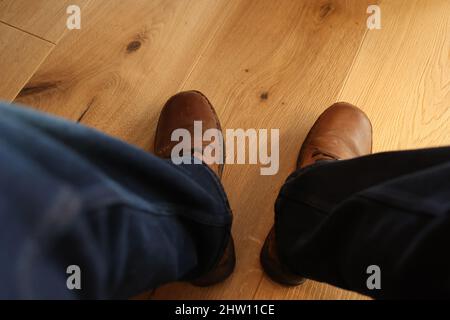 Gambe in jeans blu sotto il tavolo. Foto Stock