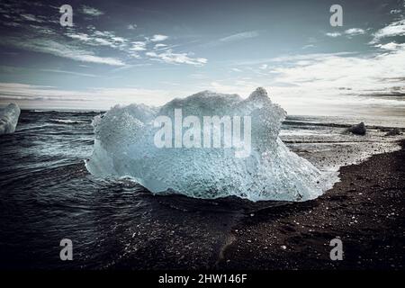 Grande blocco di ghiaccio sulla spiaggia nera Foto Stock