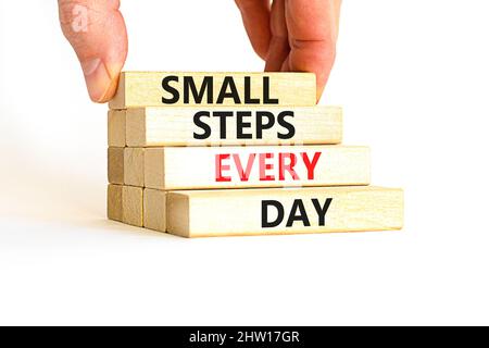 Simbolo piccoli passi ogni giorno. Parole di concetto piccoli passi ogni giorno su blocchi di legno. Mano dell'uomo d'affari. Bella tabella bianca sfondo bianco. St. Piccola Foto Stock