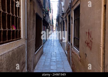 Strada stretta, vicolo nella parte vecchia di Venezia con un parroco nel retro camminando per la strada, Venezia, Italia Foto Stock