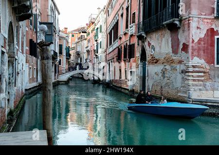 Piccolo motoscafo su un canale d'acqua a Venezia, circondato da splendide case medievali, in Italia Foto Stock