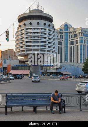 Un uomo siede su una panchina di fronte all'iconico Salute Hotel dell'era sovietica nel centro di Kiev (Kiev) in Ucraina. Foto scattata nel luglio 2013 prima della città w Foto Stock