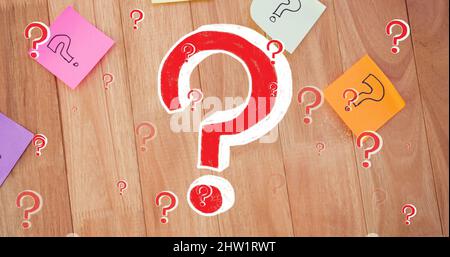 Immagine di punti interrogativi rossi su note di memo multicolore su sfondo di legno Foto Stock