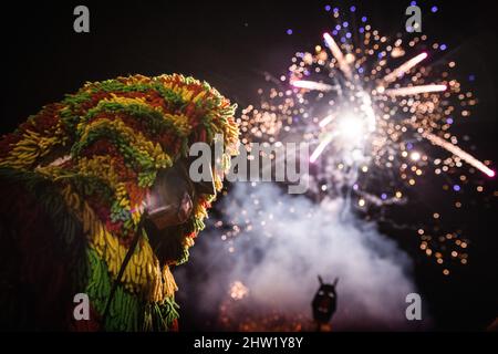 Caretos esegue rituali religiosi durante la bruciatura della maschera magica durante la celebrazione del Carnevale di Podenza. Nel villaggio portoghese di Podence, nel comune di Macedo de Cavaleiros, durante il carnevale, gli uomini indossano il costume tradizionale, noto come 'Caretos', indossano maschere in ottone o legno e indossano colorati costumi di lana. Urlano e inseguono le persone per strada per spaventarle, specialmente le donne single. Caretos de Podence è stato dichiarato patrimonio culturale immateriale dell'umanità dall'UNESCO il 2019 dicembre. L'evento si conclude con l'incendio di Entrendo (un carato gigante). Foto Stock